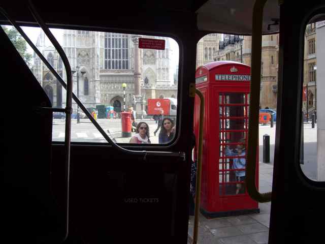 an open platform red London bus, a red telephone box, a red postbox, and Westminster Abbey.
